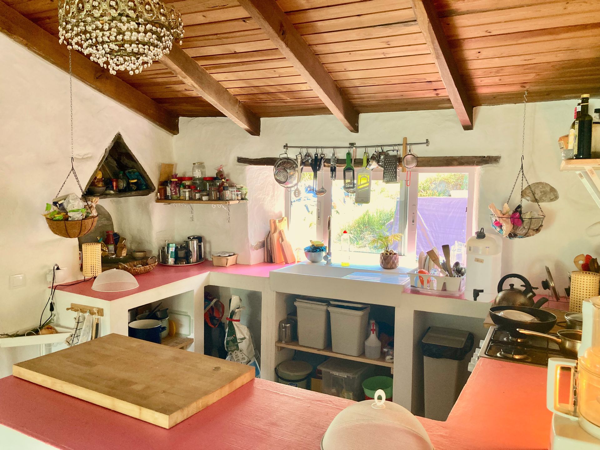 The kitchen, wood-beamed with pink counters and the window over the sink