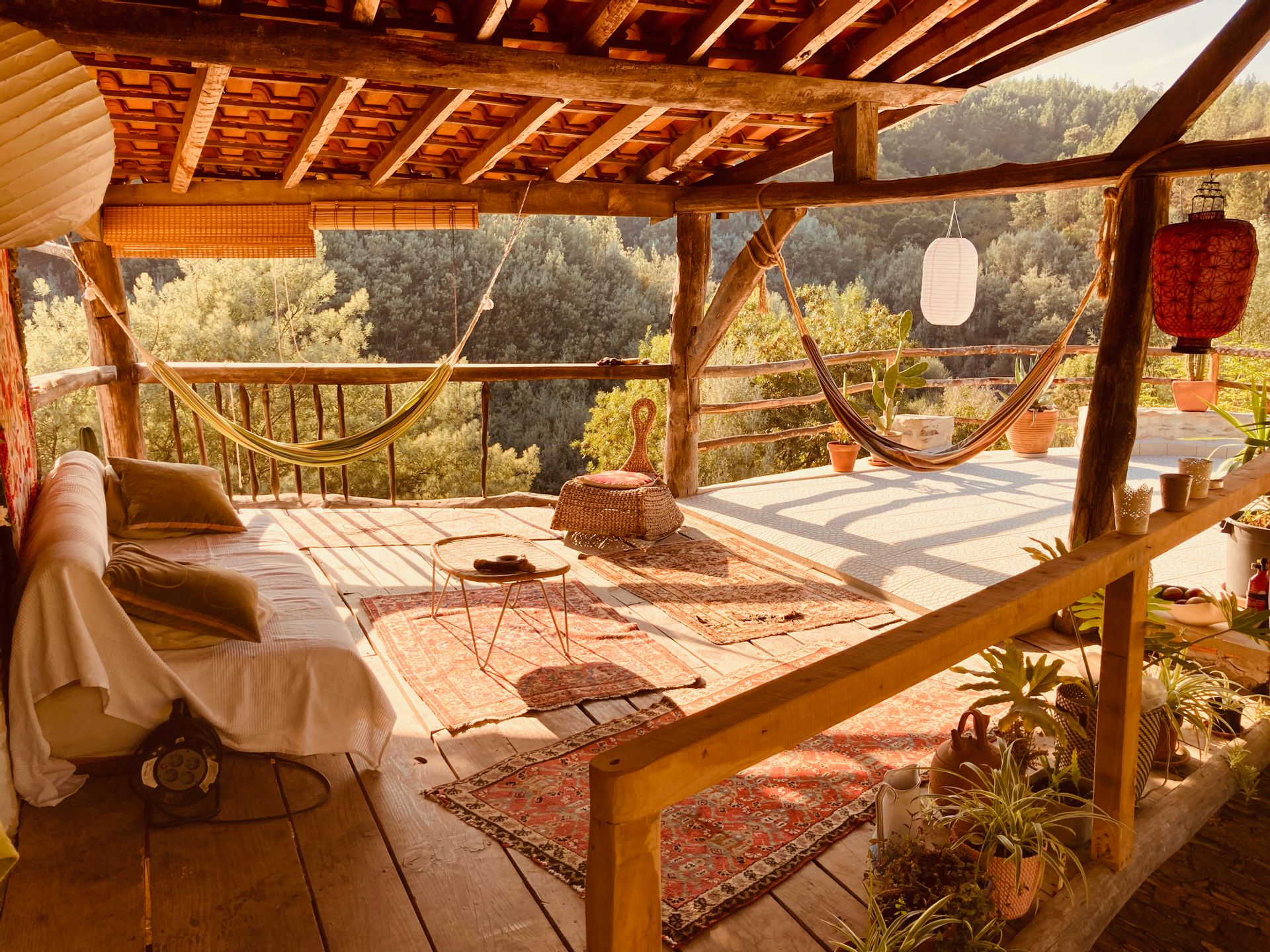 The upper terrace with hammocks and a daybed, looking out over the wooded valley
